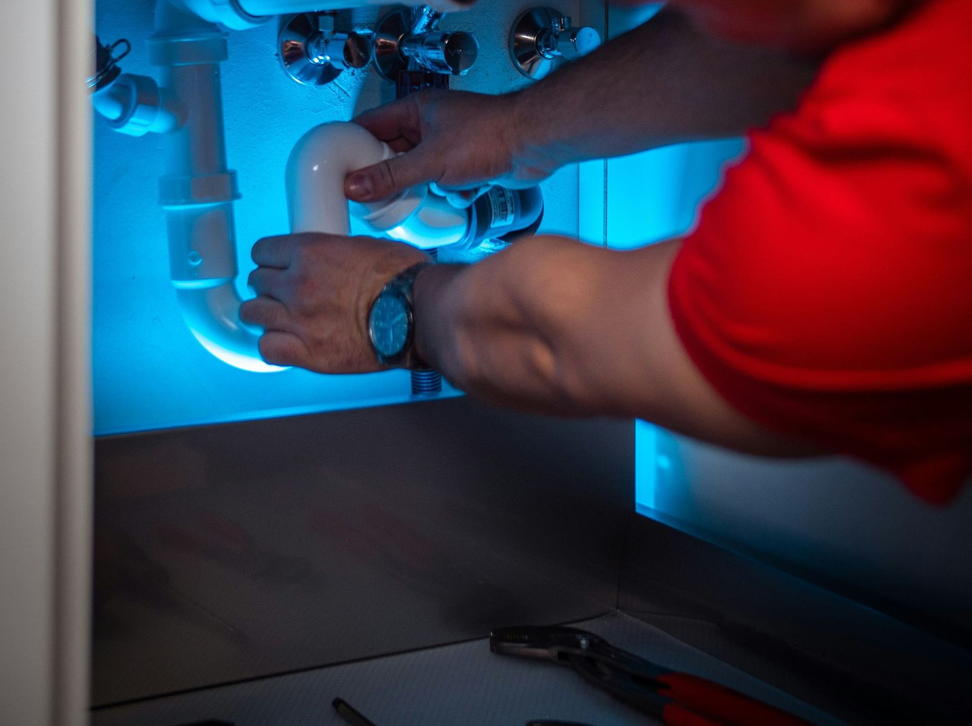a man working on a pipe in a cabinet
